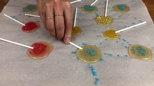 add sprinkles and push sticks into homemade sugar lollipops