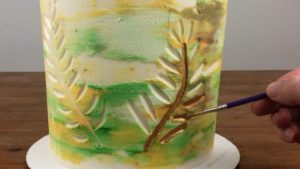 painting buttercream frosting with gold luster dust paint for edible gold cakes