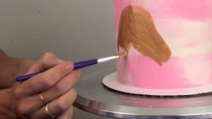 painting with gold luster dust onto smooth buttercream that has set for edible gold cakes