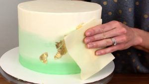 pressing gold leaf onto frosting for edible gold cakes