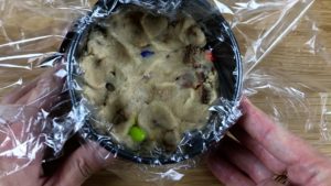 push cookie dough into pan to make a disc for cake filling