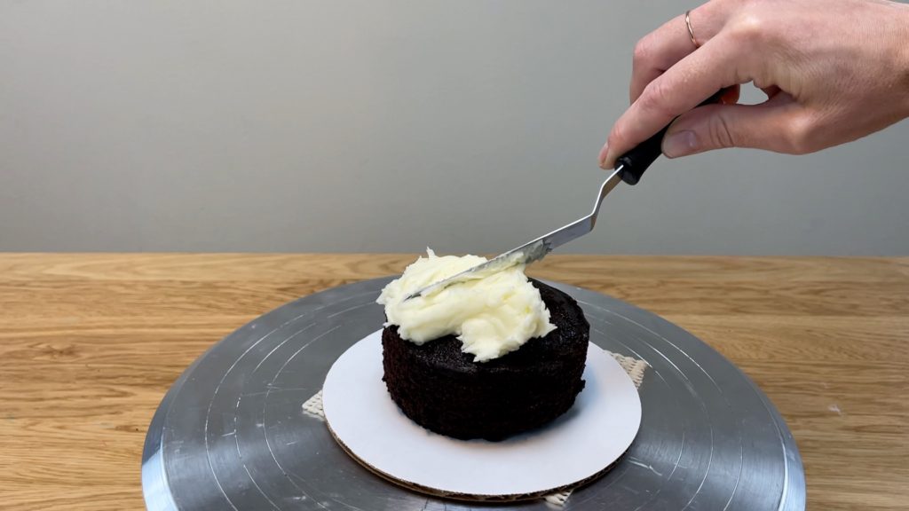 center cake on cake board and spread filling on top How to Make a Birthday Cake