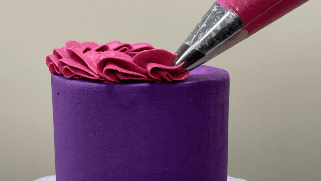 piping a wave or shell border on a cake with a 1M piping tip