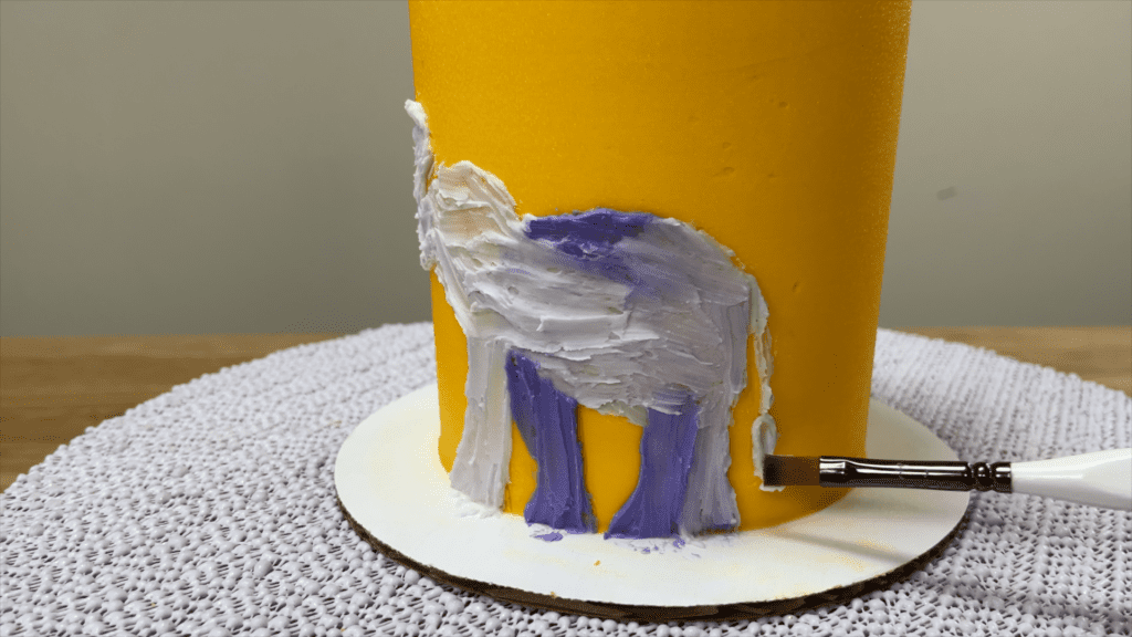 use a small paintbrush to paint with buttercream onto a cake How to Paint on Cakes