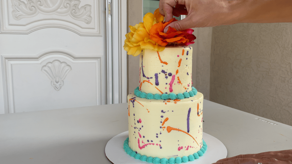 arrange artificial flowers on top of cake How To Transport A Cake 2000 Miles