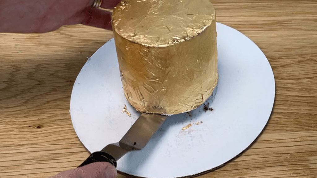 lift cake with offset spatula to transfer from cake board to cake stand or platter gold cakes 3 ways