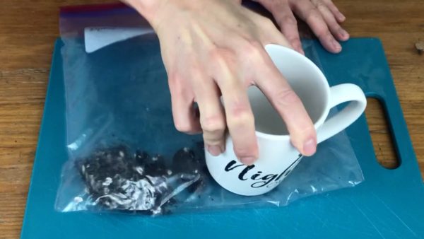 crushing oreo cookies in a ziploc bag for cookies and cream cake