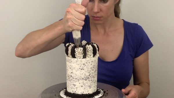 frosting swirls fill gaps between cookies and secure cookies in place on cookies and cream cake