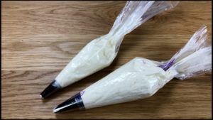 buttercream in piping bags with 1M tip and open star tip for gold buttercream pumpkins on Striped Halloween Cake