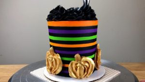 pipe 1M swirls with black buttercream onto Striped Halloween Cake With Gold Buttercream Pumpkins
