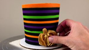 press gold buttercream pumpkins into Striped Halloween Cake