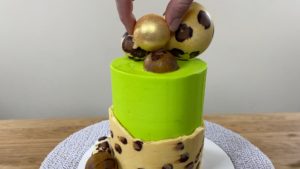 attach gold chocolate sphere to cake for trendy neon leopard print cake