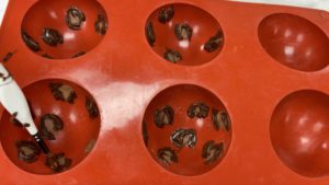 painting leopard print spots into hot chocolate bomb mold for trendy neon leopard print cake