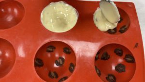 spoon chocolate into sphere mold to make leopard print chocolates for trendy neon leopard print cake