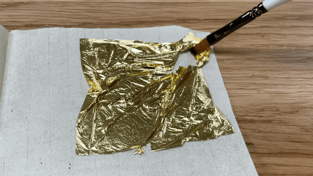 pick up golf leaf with paintbrush How To Use Gold Leaf On Cakes