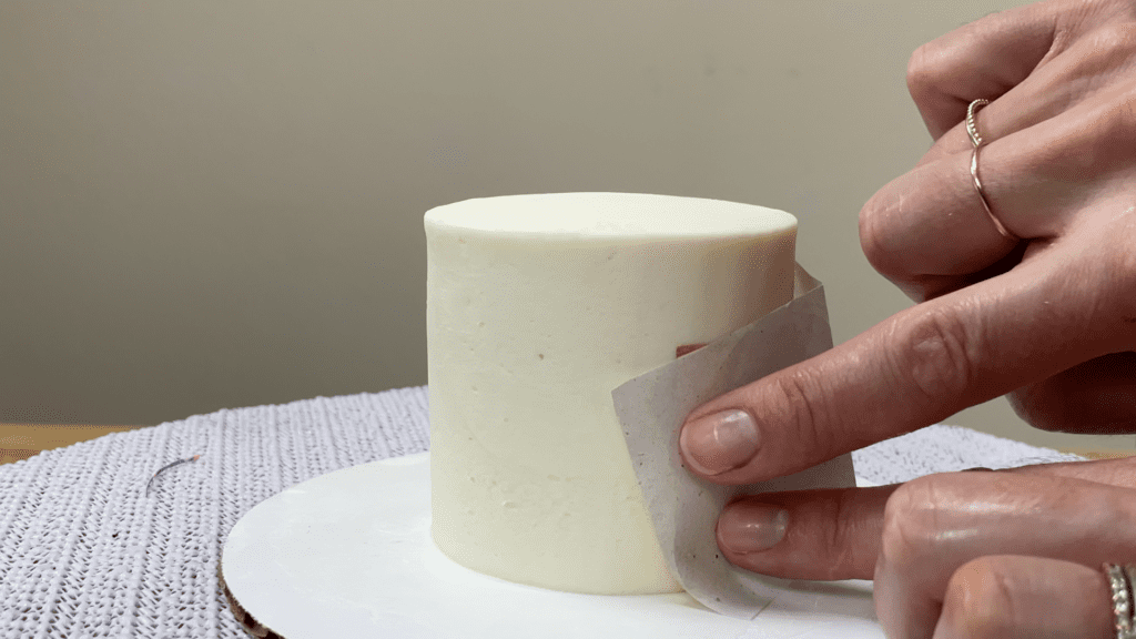 press gold leaf against cake through backing paper How To Use Gold Leaf On Cakes