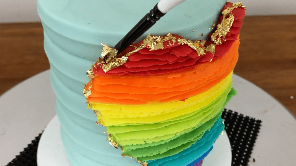 press gold leaf onto outline of piping How To Use Gold Leaf On Cakes