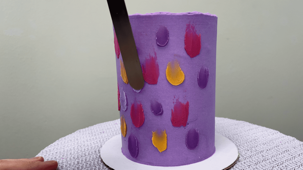 spread buttercream dots onto cake with offset spatula 5 Cakes You Can Decorate in 5 Minutes