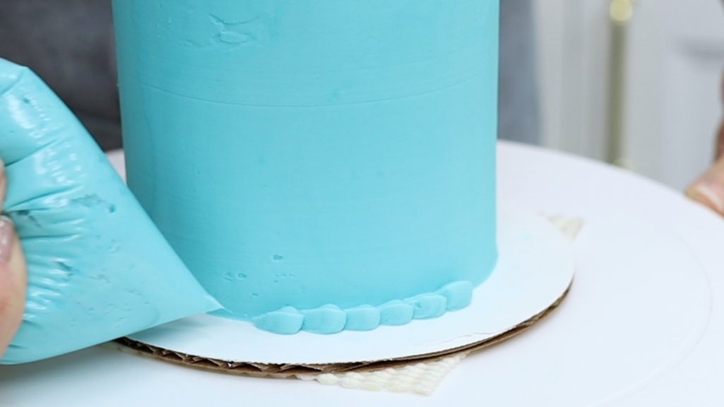 piping a beaded border around a cake with a ziplock bag Save or Splurge Improve your Cake Decorating with these Tools!