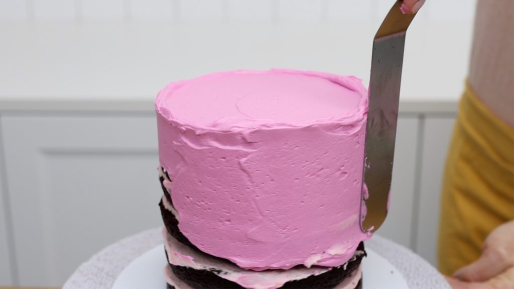 applying a crumb coat of frosting to a frozen cake How To Freeze Cakes