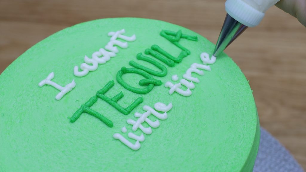 piping a message onto a cake with buttercream and a piping bag