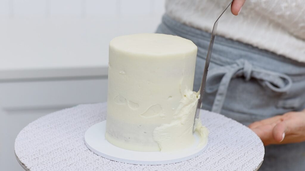 How to Fix a Leaning Cake by spreading more frosting onto the crumb coat | British Girl Bakes