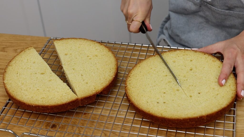 cut cake layer in half to make semicircles How To Make A Rainbow Cake | British Girl Bakes