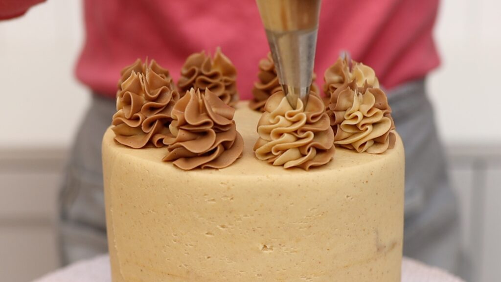 how to pipe two tone 1M swirls onto Chocolate Peanut Butter Cake | British Girl Bakes