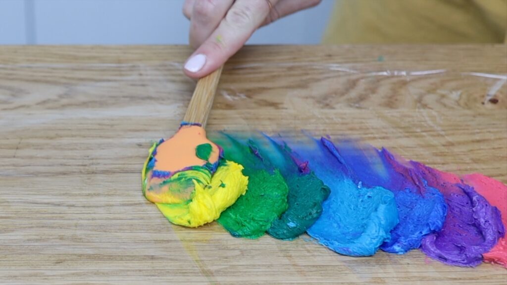 spread leftover Rainbow buttercream frosting onto saran wrap for rainbow piping - 5 Minute Cake Decorating | British Girl Bakes