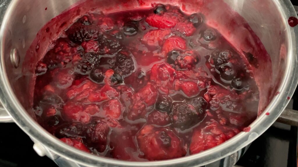 cook berries to make berry frosting to decorate a cake with berries