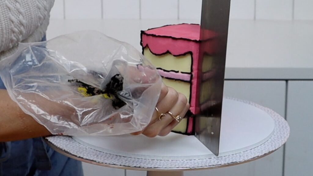 how to pipe straight lines onto a comic cartoon cake using a cake comb