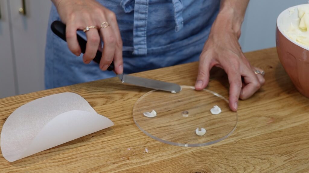 attach parchment circle to acrylic disc with four small dots of buttercream