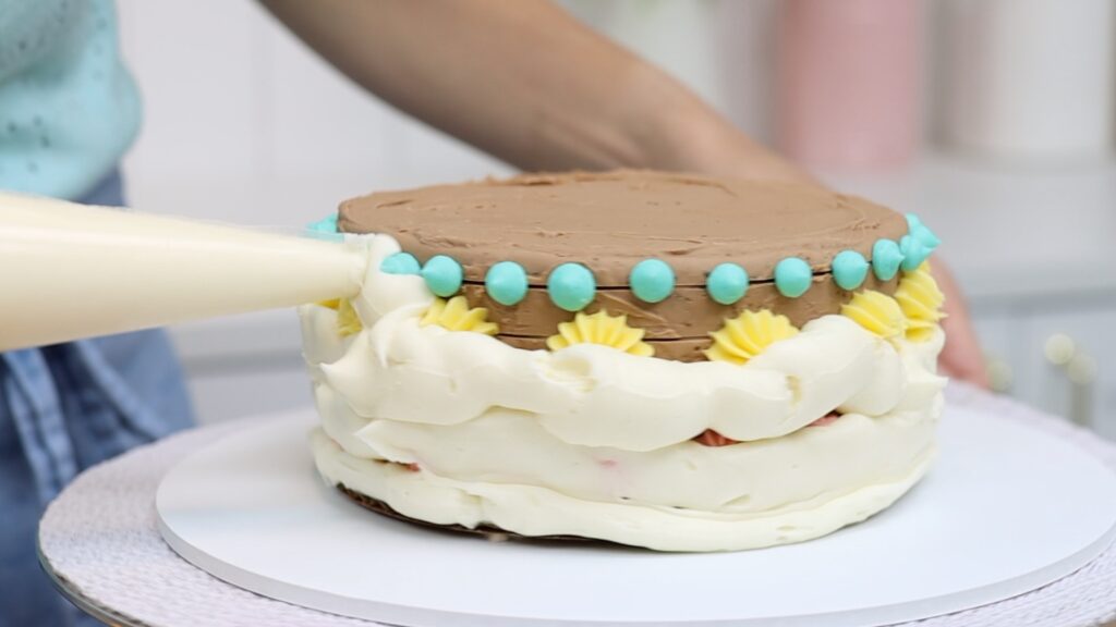 covering a cake with piped frosting before freezing and scraping