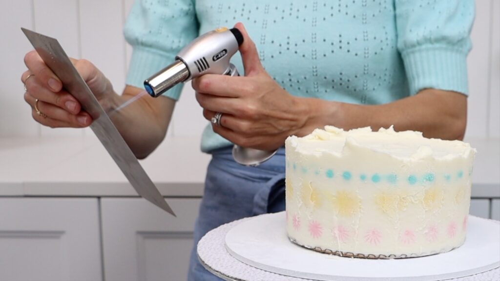 how to use a blowtorch with a metal cake comb to smooth frosting on a cake