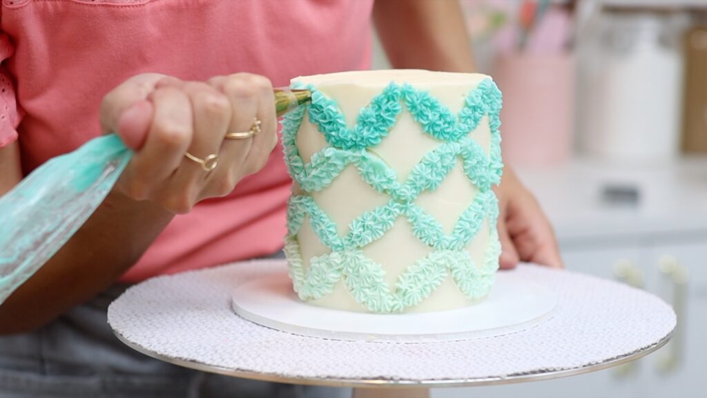 piping a circular pattern onto a cake to make a flat parttern with facelift frosting