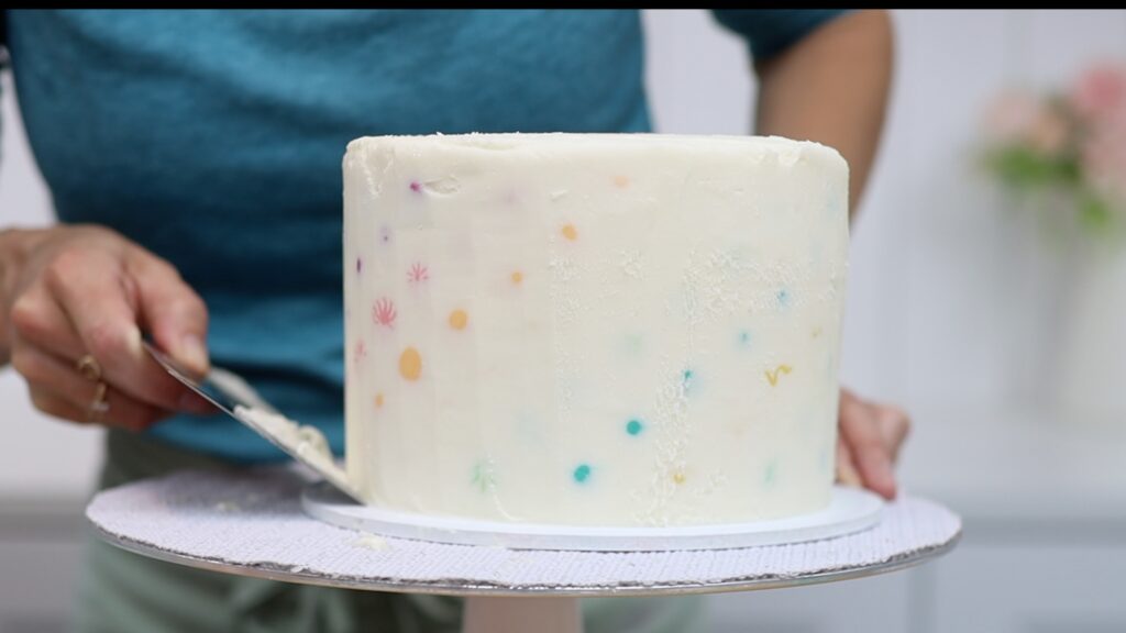 scrape up and around cake to take off layers of frosting to reveal a cross section of piping