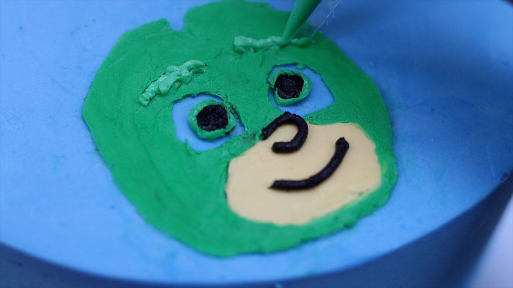 piping details onto a character on a cake with buttercream