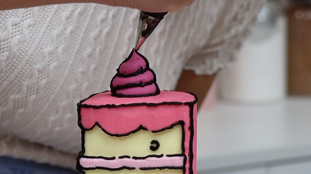 piping outlines onto a cartoon cake slice