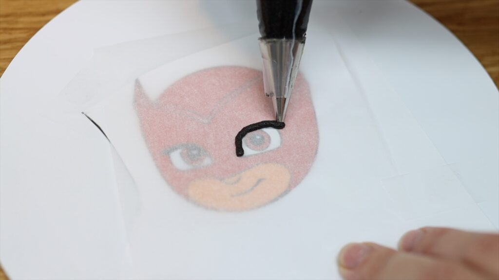 tracing a character with buttercream for a cake
