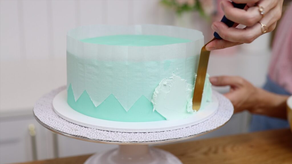 spread buttercream over homemade parchment stencil on cake