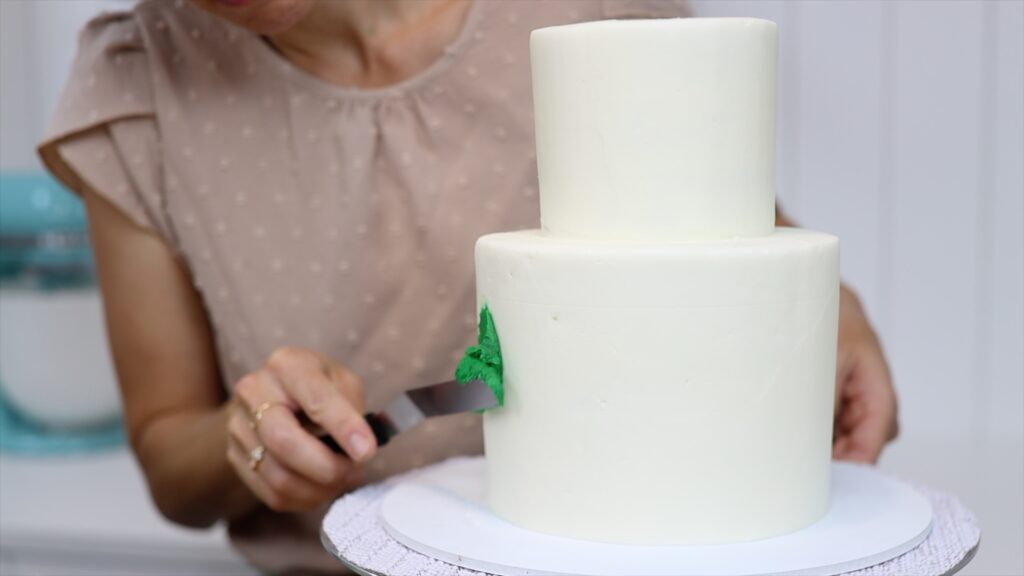 spreading buttercream onto a cake like paint