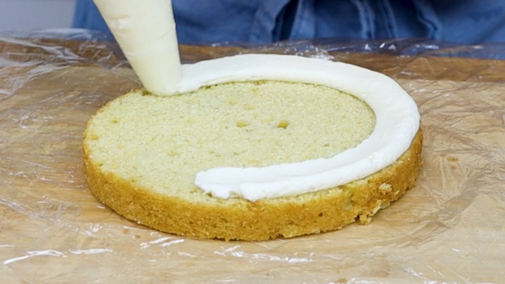 Piping a buttercream ring or dam onto a cake layer