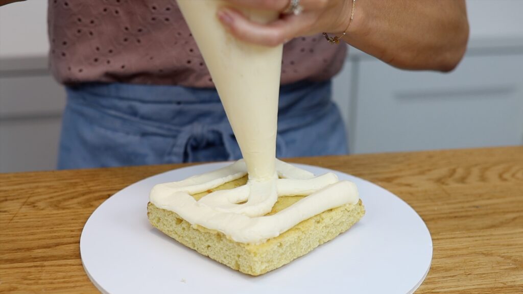 piping filling onto a square cake