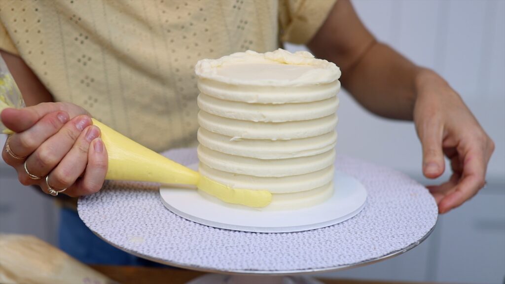 piping a striped border onto a cake