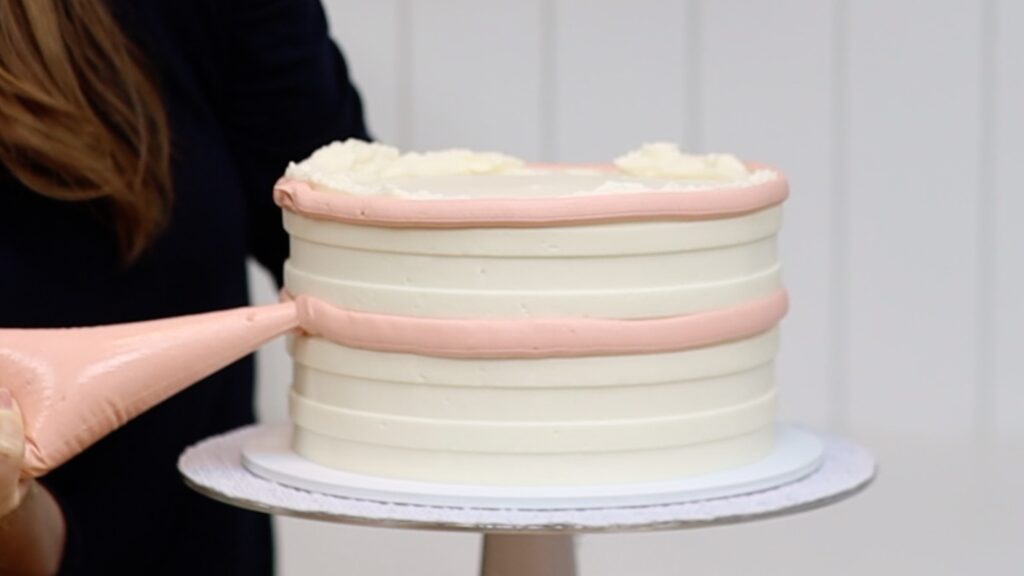 piping buttercream stripes onto a cake