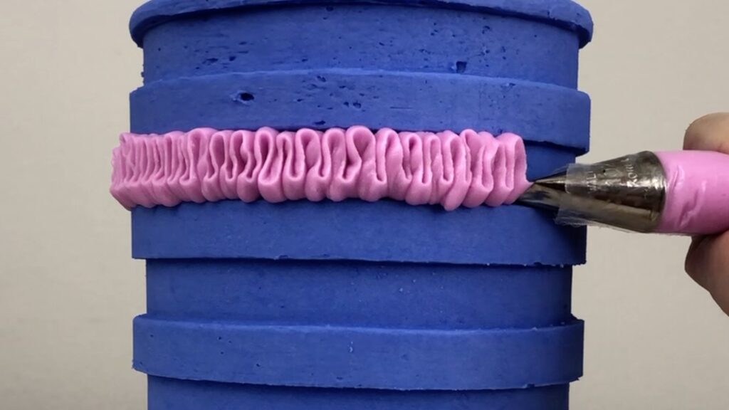 piping ruffles into the grooves made by a striped cake comb