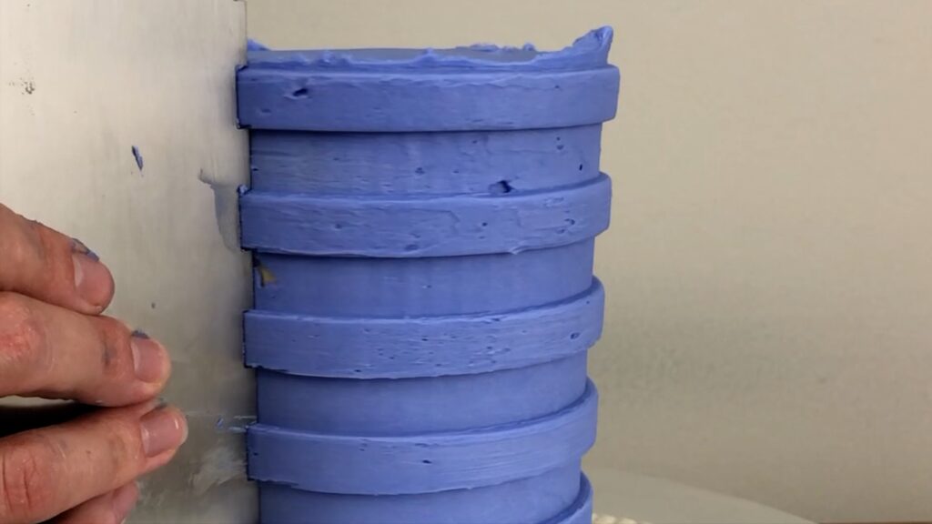 use a striped cake comb to make grooves in the frosting on a cake