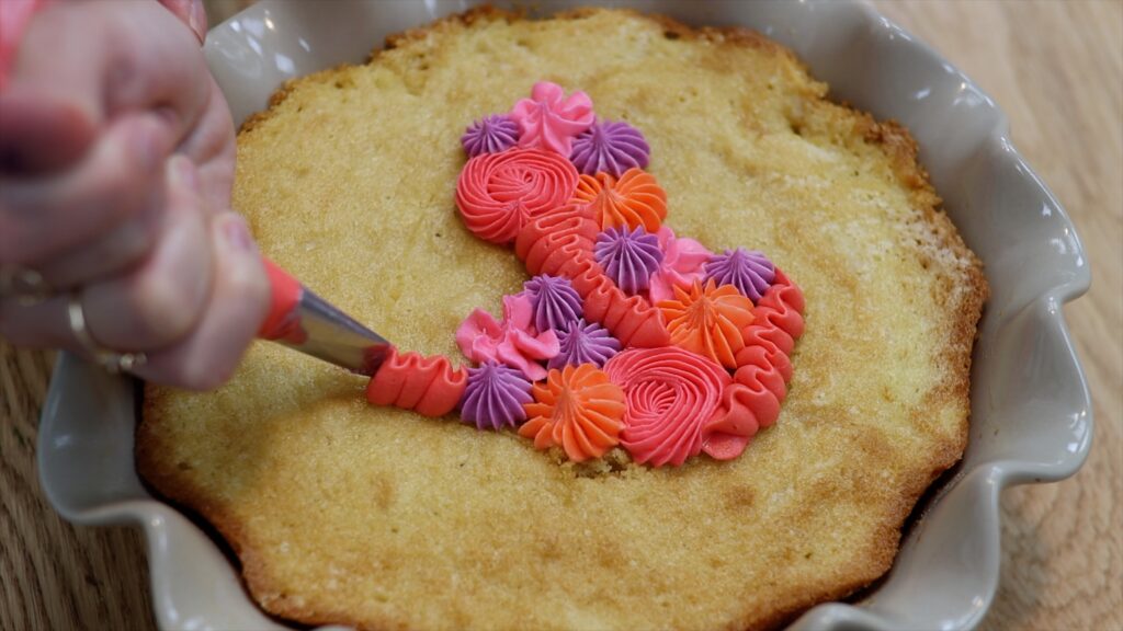 piping onto a tray bake cake in a casserole dish or baking dish or pie dish