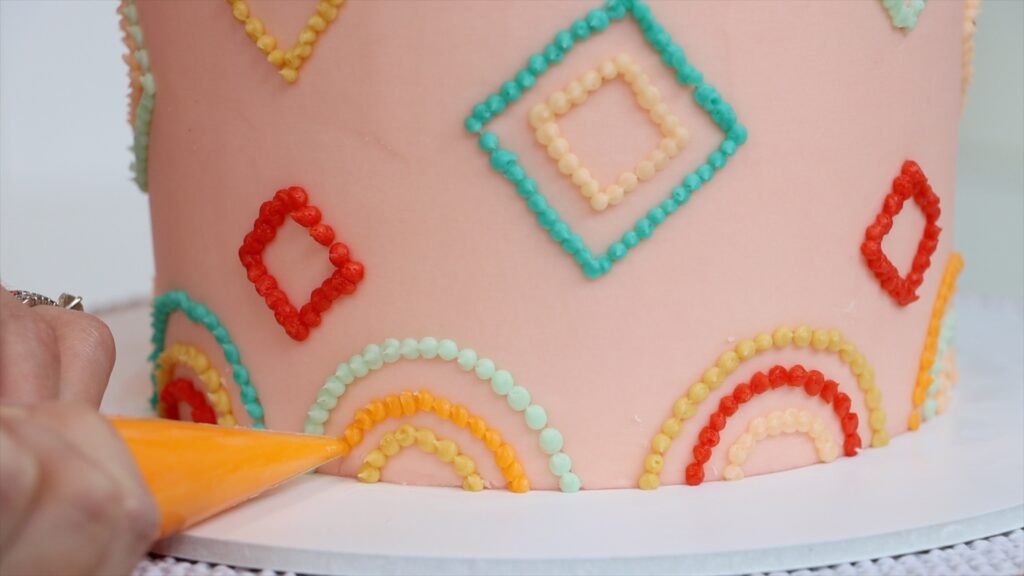 using a piping bag with no piping tip for cake decorating on a pointillist cake