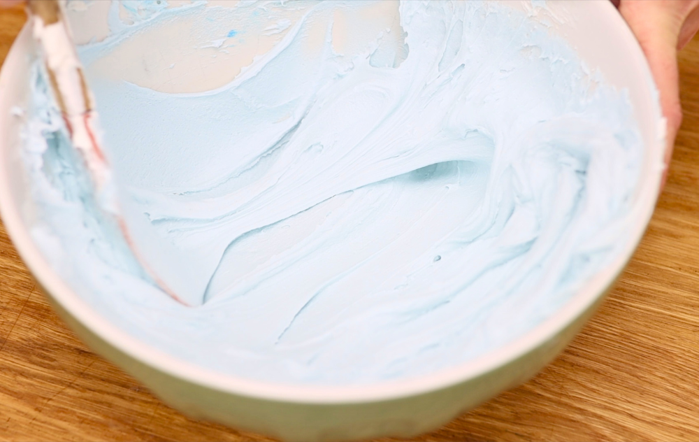 Knocking a spatula of buttercream against a bowl to push out air
